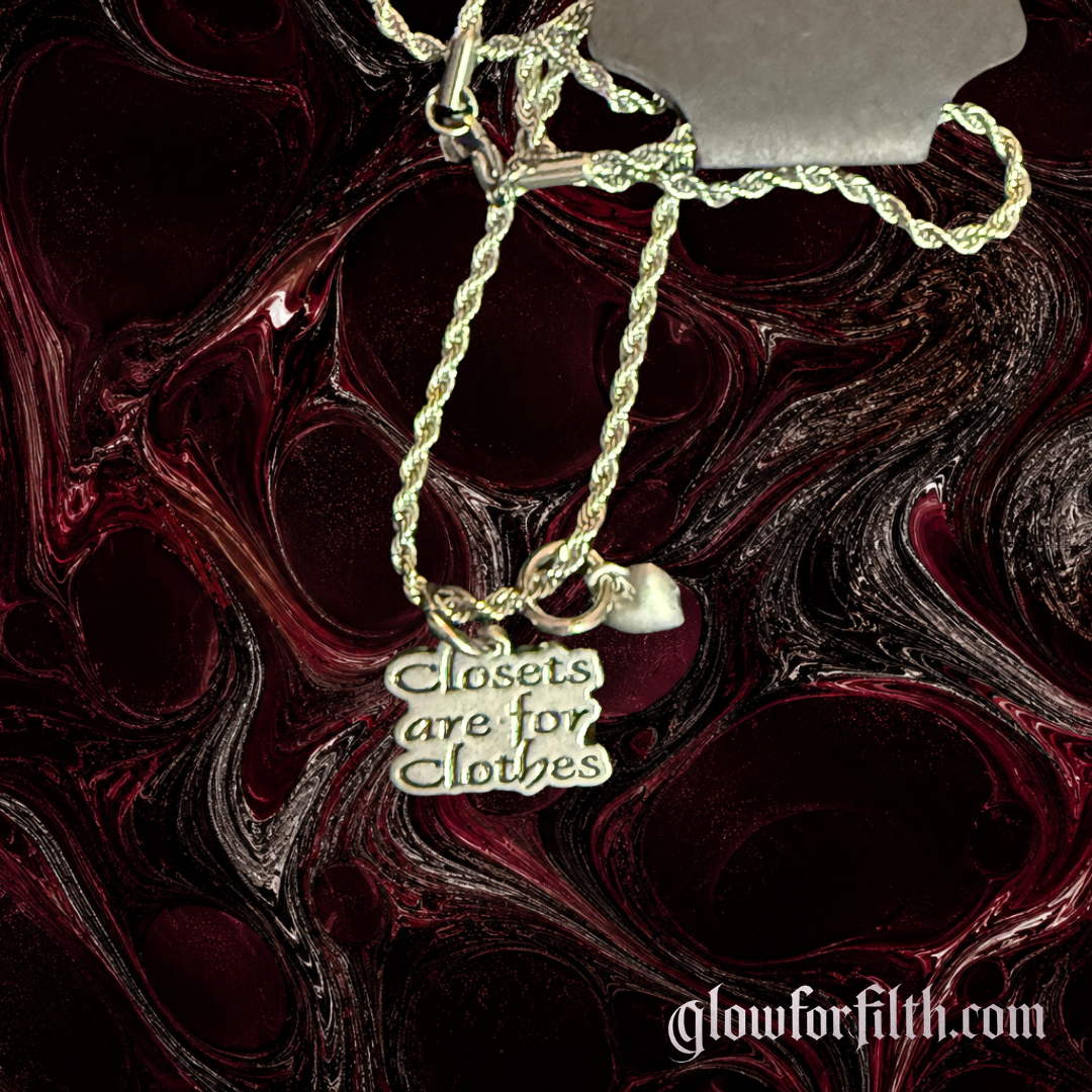 American pewter Closets Are For Clothes necklace with heart accent charm on a stainless steel rope chain displayed against a dark red and black background.