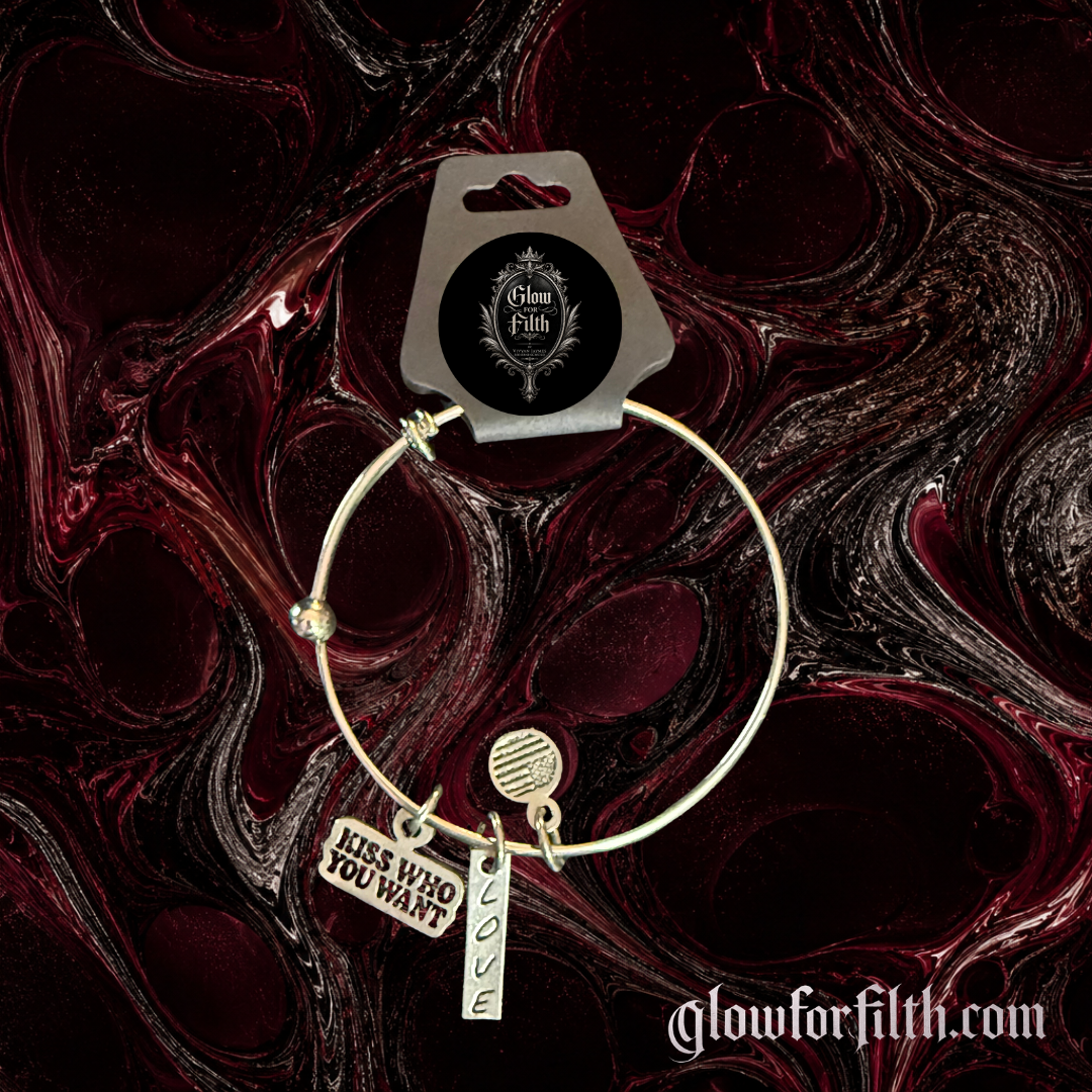 Silver-tone expandable bangle bracelet featuring lead-free pewter Kiss Who You Want and Love charms displayed on a burgundy and black gothic background.