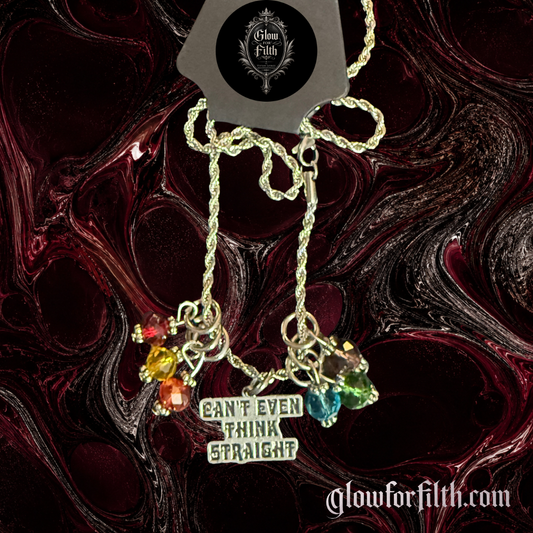 Silver-tone necklace featuring a "Can't Even Think Straight" charm accented with rainbow-colored crystal beads displayed on a gothic burgundy and black background.