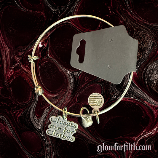 Expandable silver-tone charm bracelet featuring a pewter Closets Are For Clothes charm, heart accent, and American flag charm against a dark red and black background.