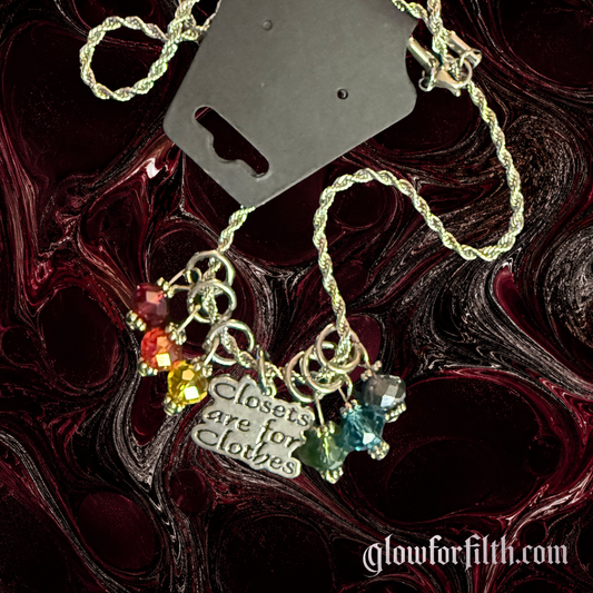 American pewter Closets Are For Clothes necklace with six rainbow crystal accent beads on a stainless steel rope chain against a dark red and black Glow for Filth background.