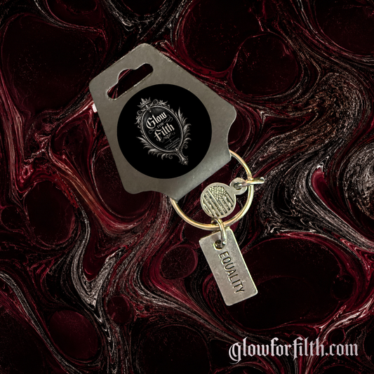 Silver-tone keychain featuring a lead-free pewter Equality charm displayed on a gothic burgundy and black marbled background.
