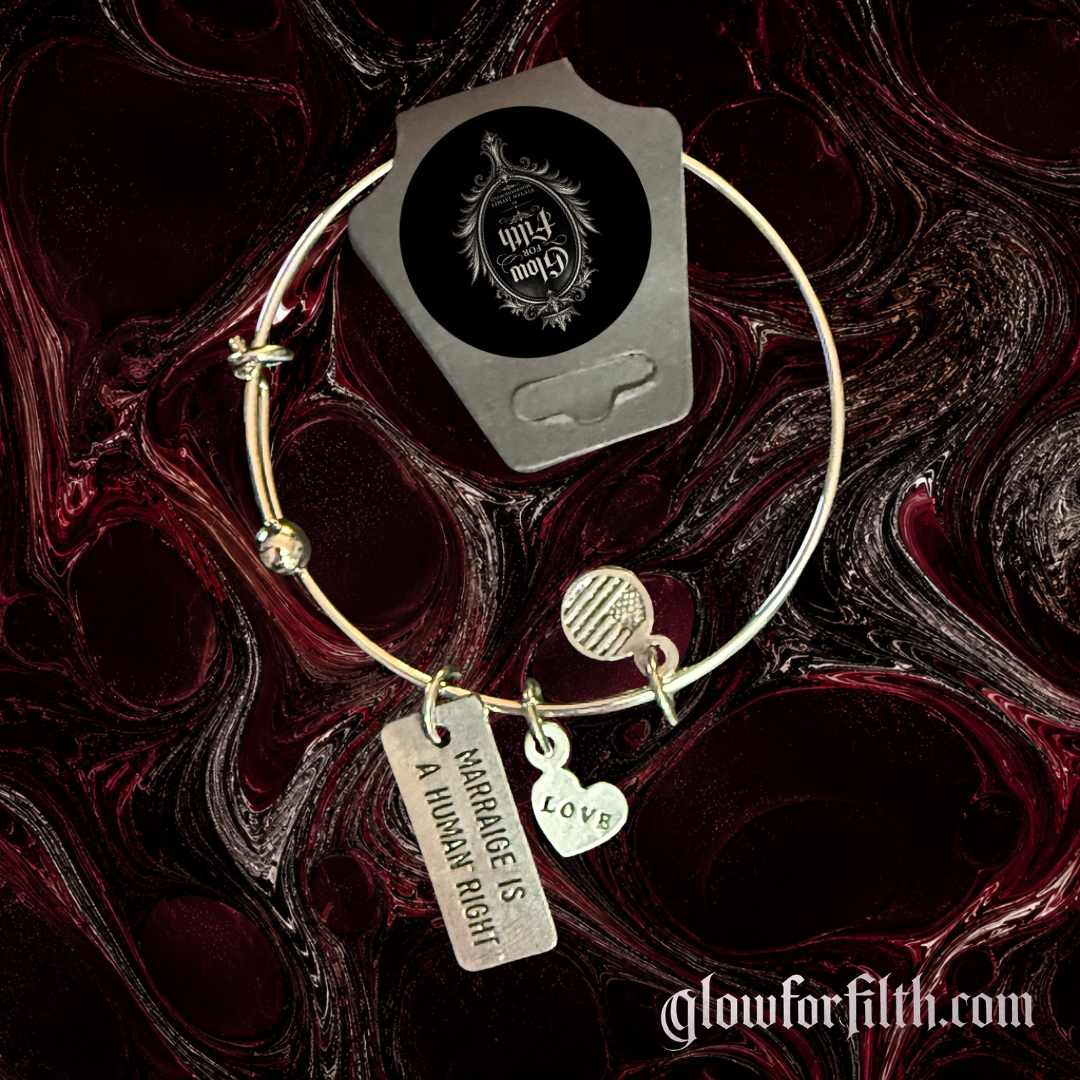 Silver-tone expandable bangle bracelet featuring a lead-free pewter Marriage Is a Human Right charm and a silver-tone LOVE heart charm displayed on a gothic burgundy and black marbled background.