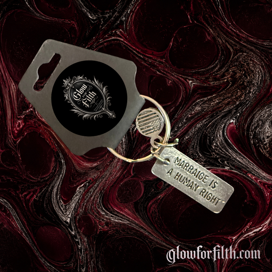 Silver-tone keychain featuring a lead-free pewter Marriage Is a Human Right charm displayed on a gothic burgundy and black marbled background.