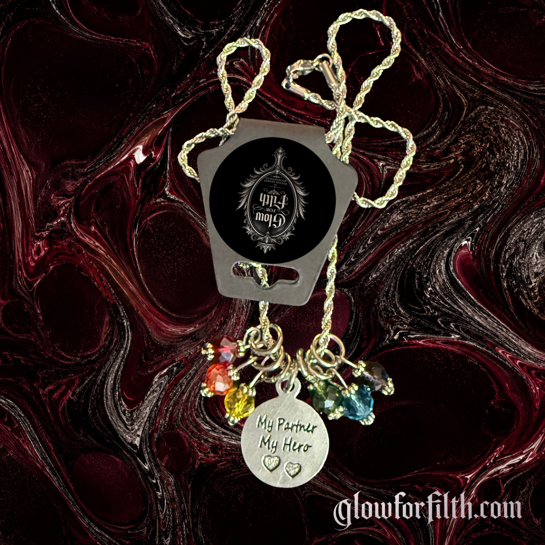 Silver-tone rope chain necklace featuring a lead-free pewter My Partner My Hero charm accented with rainbow crystal beads on a gothic burgundy and black marbled background.